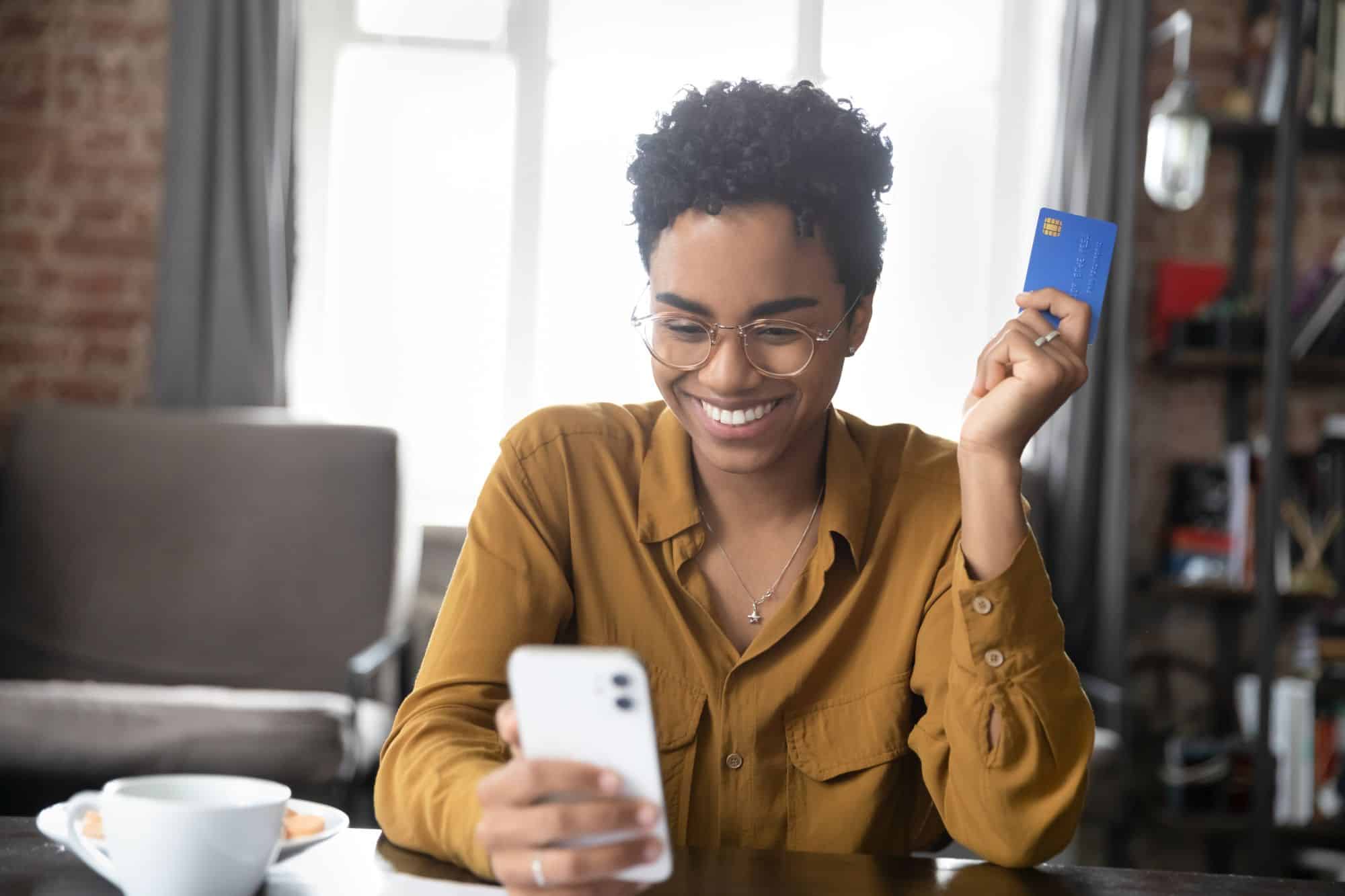 Woman smiling with card out looking at phone