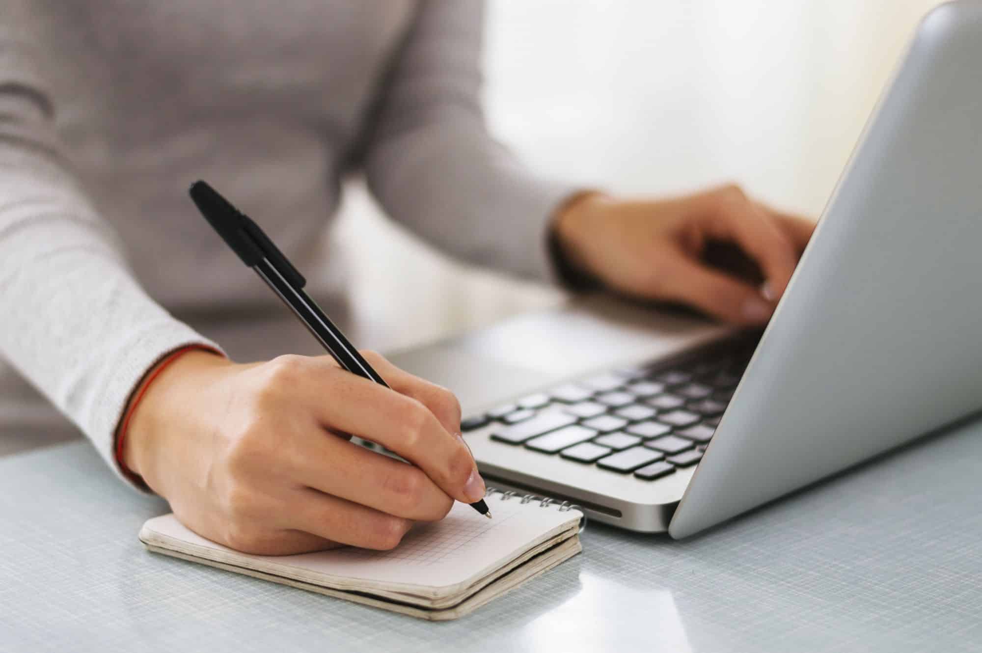 Person writing at computer