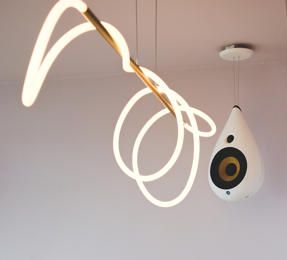 Close up image of a swirling light fixture attached to the ceiling alongside a speaker