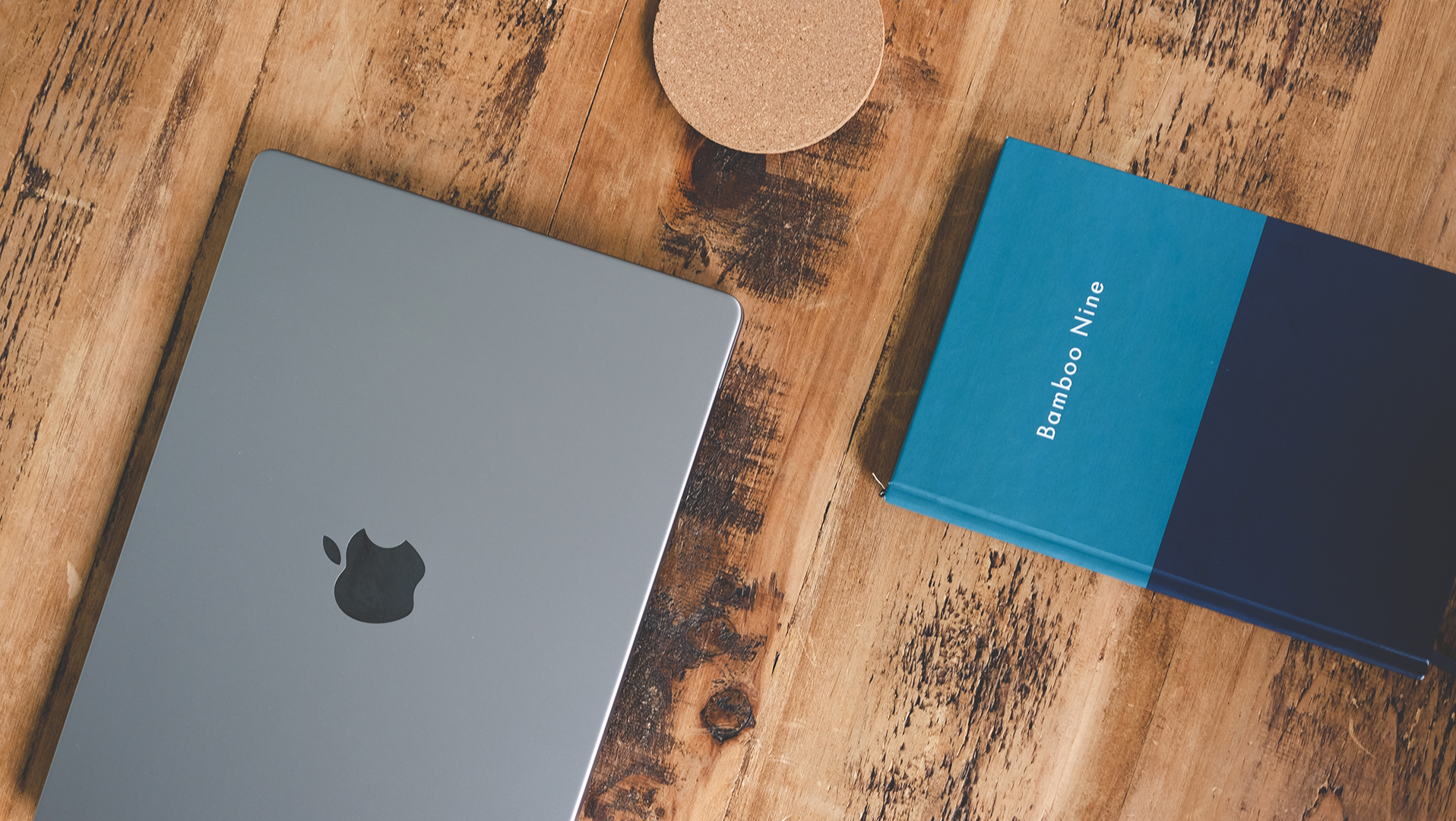 Laptop and notebook embossed with Bamboo Nine lettering on a wooden table