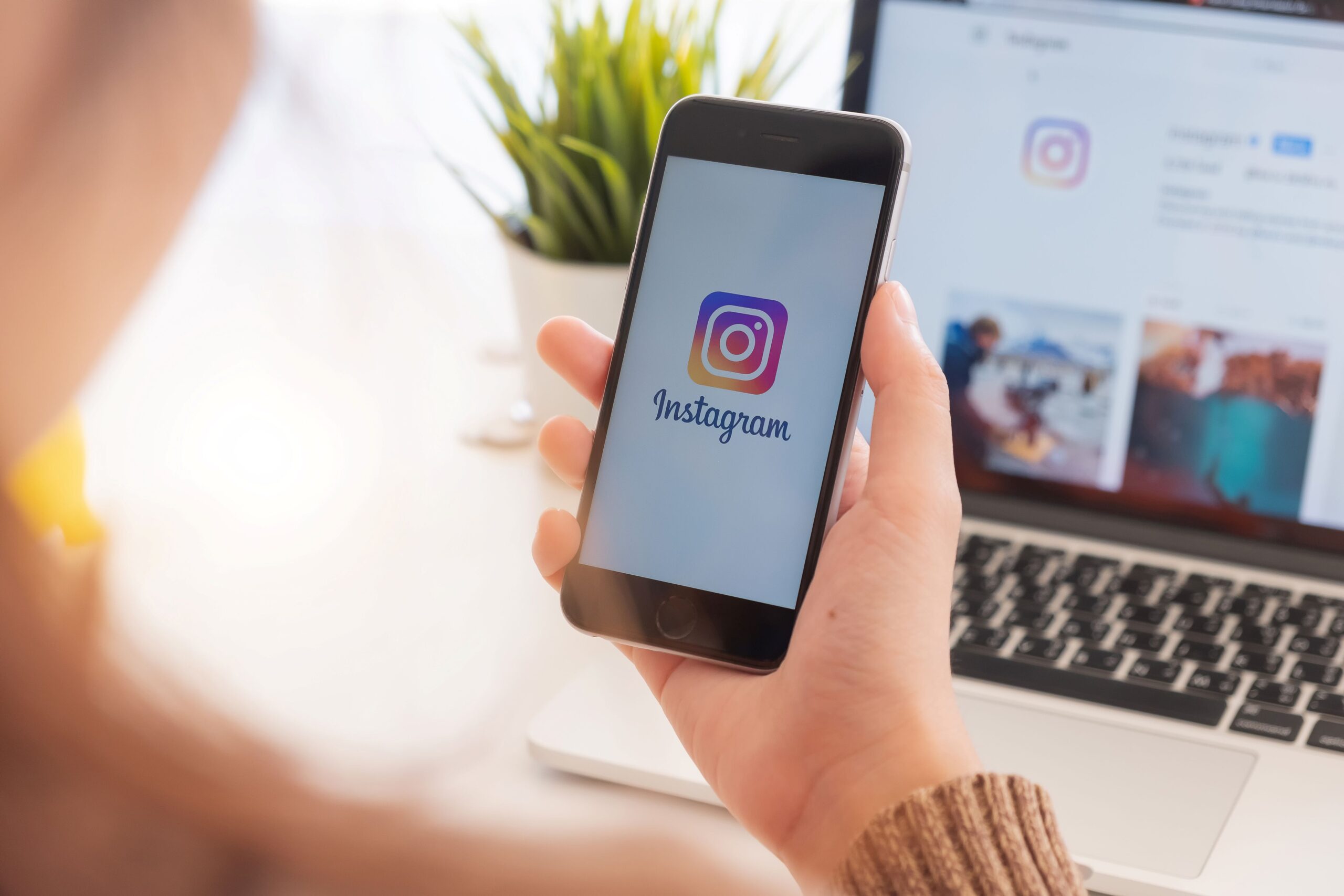 User holding a phone up as Instagram loads